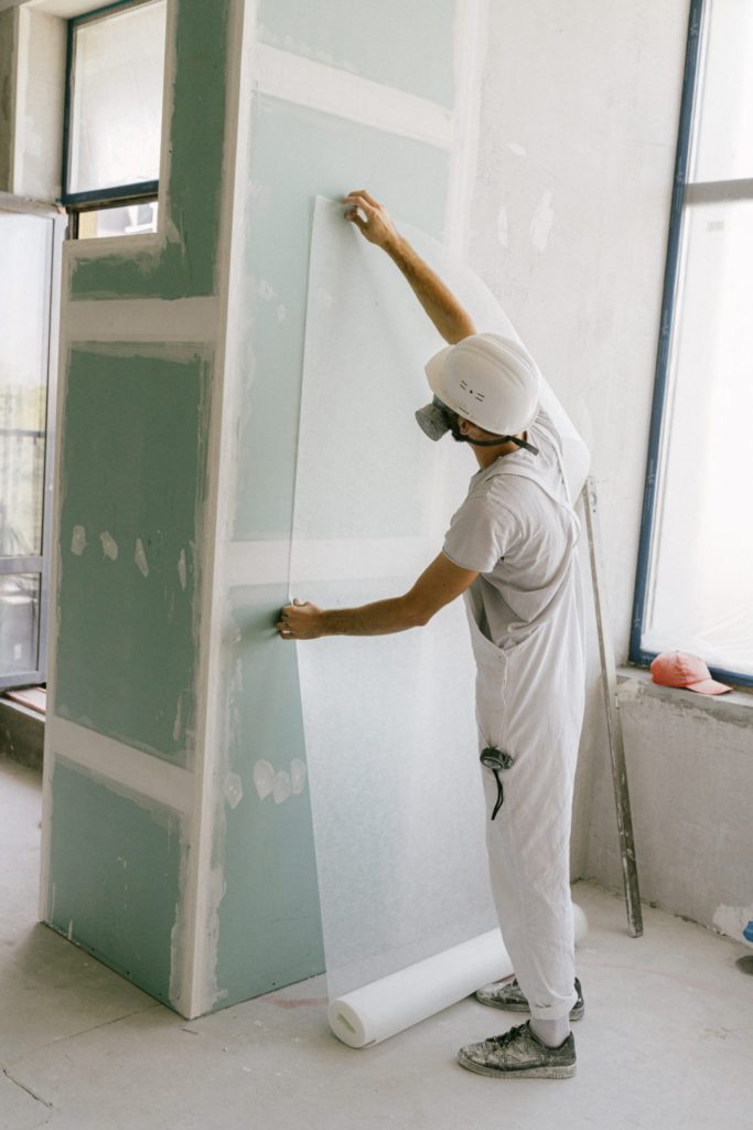 Man dressed in white installing drywall