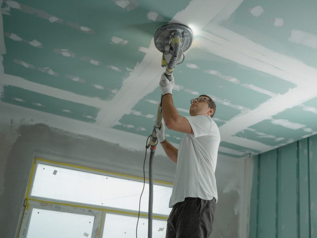 Man sanding ceiling of a newly constructed home