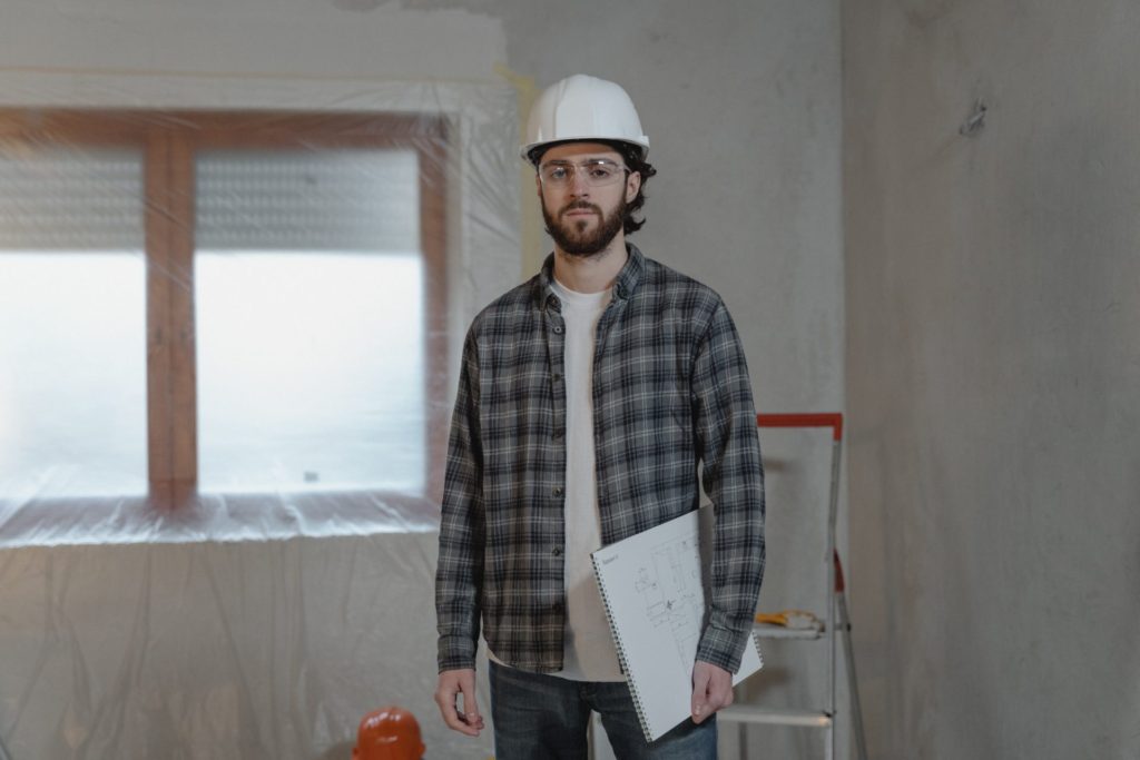 Construction worker standing in the middle of a room holding a clipboard